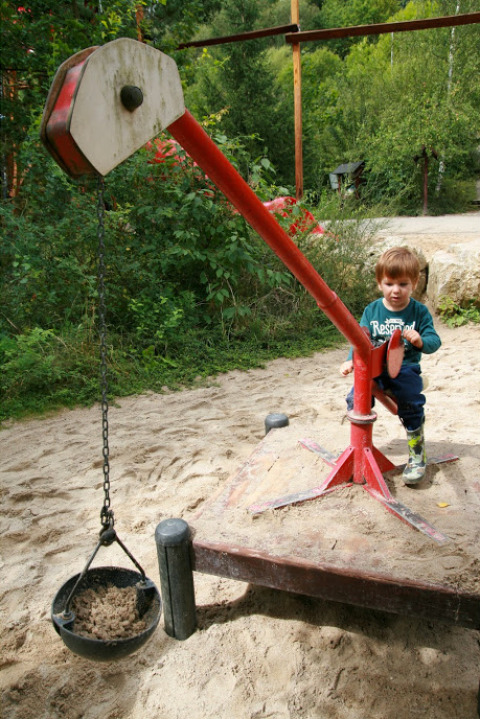 Barn leger med en sandgravemaskine på legepladsen hos Familiepark Sottrum - Boomhutten Nedersaksen.