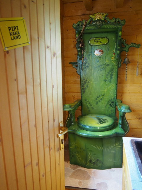 Groen toilet als troon in een houten hut bij Familiepark Sottrum - Boomhutten Nedersaksen glamping locatie.