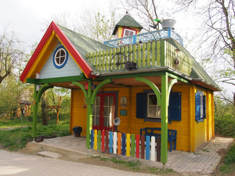 Kleurrijke houten boomhut met balkon en hek, ideaal voor glamping in Familiepark Sottrum, omringd door natuur.