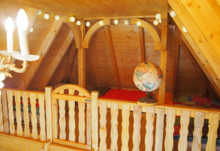 Boomhutinterieur met houten balustrade, globe, lichten en bedden in Familiepark Sottrum, Nedersaksen.