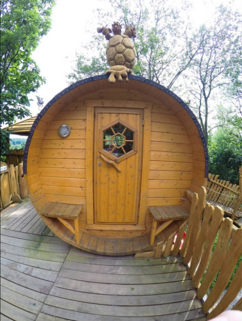 Glamping-Unterkunft im Familiepark Sottrum, ein rundes Holzhaus mit Schildkrötenskulptur auf dem Dach.