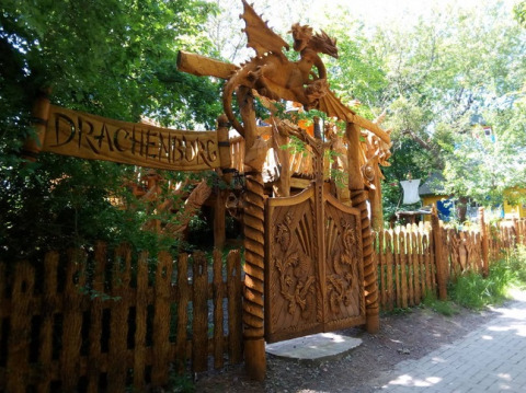 Entrance to Familiepark Sottrum - Boomhutten Nedersaksen, with wooden dragon gate and lush greenery surrounding.