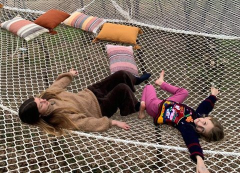 Mother and daughter relaxing on a large net with cushions at Azienda Agricola Il Granello Glampingtent Italy.