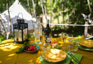 Tavolo all'aperto con vino, snack e lanterna vicino alla tenda glamping Azienda Agricola Il Granello in Italia.