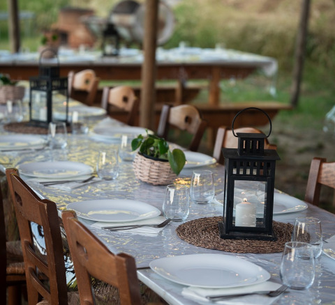 Buiten eettafel met lantaarns, planten en servies bij Azienda Agricola Il Granello glampingtent in Italië.