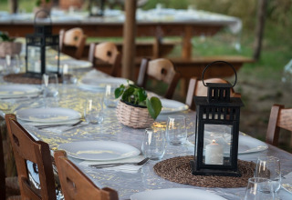 Buiten eettafel met lantaarns, planten en servies bij Azienda Agricola Il Granello glampingtent in Italië.