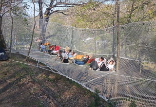 Een groep mensen ontspant op een groot net tussen de bomen bij Glampingtent Italië van Azienda Agricola Il Granello.