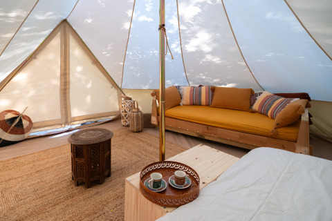 Indvendig udsigt over en luksuriøs glampingtelt med komfortable møbler og rustik dekoration i Italien.