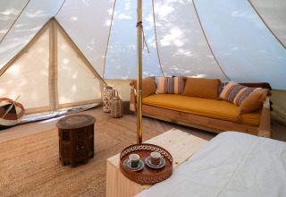 Vista interna di una tenda glamping con divano accogliente, tavolino in legno e arredi eleganti a Il Granello, Italia.