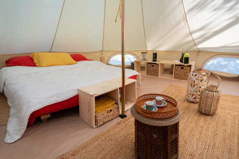 Interno della tenda glamping di Azienda Agricola Il Granello in Italia, con letto matrimoniale e arredi eleganti.
