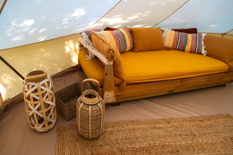 Gemütliches Glamping-Zelt bei Azienda Agricola Il Granello mit gelbem Sofa und Korbdekoration.