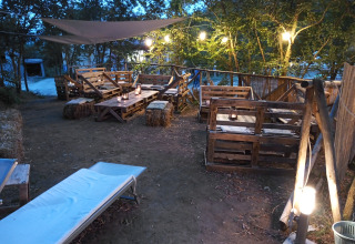 Zona de glamping al aire libre en Azienda Agricola Il Granello con muebles de palets y faroles en Italia.