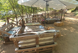 Gemütlicher Sitzbereich im Freien mit Palettenmöbeln, Strohsitzen und Sonnenschirm bei Il Granello.