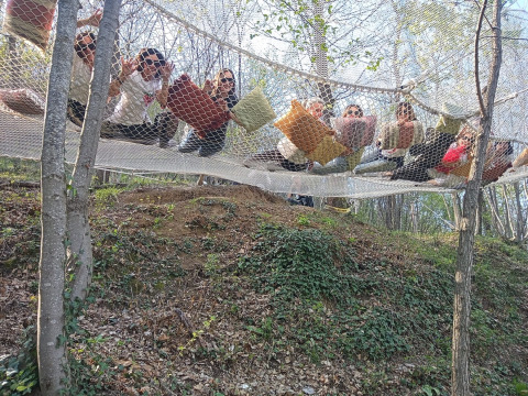 Een groep mensen ontspant op een net met kussens in het bos bij Azienda Agricola Il Granello Glampingtent Italië.