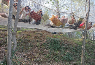 Een groep mensen ontspant op een net met kussens in het bos bij Azienda Agricola Il Granello Glampingtent Italië.