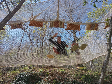 Deux personnes se détendent sur un filet suspendu entre des arbres à Azienda Agricola Il Granello Glampingtent Italie.