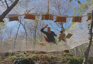 Due persone si rilassano su una grande rete sospesa tra gli alberi presso Azienda Agricola Il Granello Glampingtent Italia.