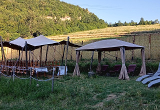Glamping site with tents, wooden chairs and loungers on a grassy field at Il Granello in Italy.