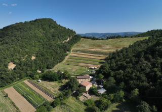 Vista aérea de Azienda Agricola Il Granello, glamping y campos agrícolas rodeados de colinas verdes en Italia.