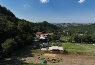 Glamping tents at Azienda Agricola Il Granello in Italy, set amid verdant hills and farm buildings on a sunny day