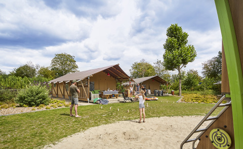 Familie nyder fritiden foran glamping-telt ved Recreatiepark TerSpegelt LoungeLodge i Noord-Brabant.