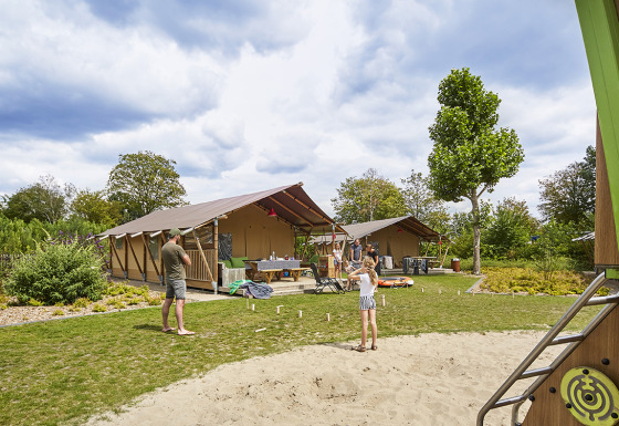 Familie nyder fritiden foran glamping-telt ved Recreatiepark TerSpegelt LoungeLodge i Noord-Brabant.