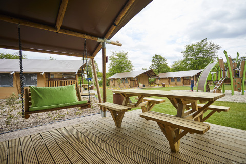Glampingaccommodatie bij Recreatiepark TerSpegelt, Noord-Brabant met houten terras, schommel en speeltuin.