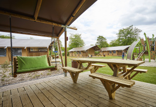 Alojamiento glamping en Recreatiepark TerSpegelt, Noord-Brabant con terraza de madera, columpio y área de juegos.
