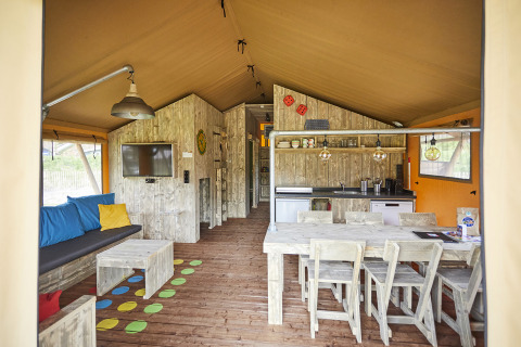 Interior view of a luxury glamping lodge with dining table, sofa and kitchen at TerSpegelt, Noord-Brabant.