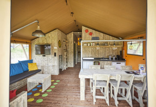 Interieur van luxe glampinglodge met eettafel, keuken en zithoek bij TerSpegelt, Noord-Brabant.