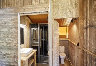 Moderne badeværelse i træ med toilet, bruser og håndvask på LoungeLodge Glamping i Noord-Brabant, Holland.