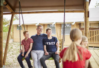 Familia disfruta de un columpio al aire libre mientras hace glamping en LoungeLodge, Recreatiepark TerSpegelt, Noord-Brabant.