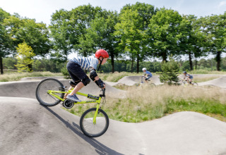 Des enfants font du vélo sur une pumptrack au Recreatiepark TerSpegelt LoungeLodge Glamping, Noord-Brabant.