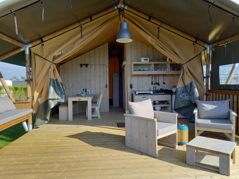 Luxe glamping safaritent met houten terras, moderne meubels en een buitenruimte in Noord-Holland.