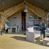 Luxury glamping safari tent with wooden deck, modern furnishings, and outdoor seating area in Holland.