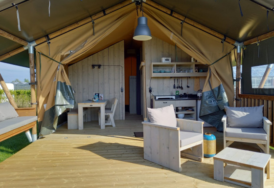 Luksuriøs glamping-safaritelte med trædæk, moderne møbler og udendørs opholdsområde i Holland.