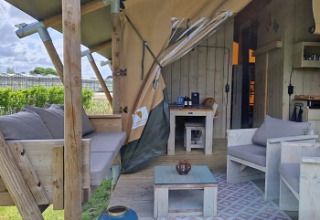 Buiten glamping accommodatie met houten meubels bij Glamping Heemskerkerduin in Noord-Holland.
