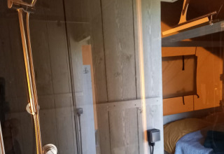 Indvendig udsigt af en glamping safari-telt i Heemskerkerduin med bruser og soveområde i Holland.