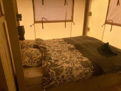 Glamping Heemskerkerduin: tienda tipo safari en Noord-Holland con cama doble y luz ambiente cálida.