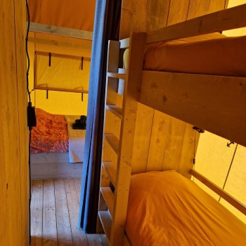 Vista interior de Glamping Heemskerkerduin - Safaritenten en Noord-Holland con literas y cama doble.