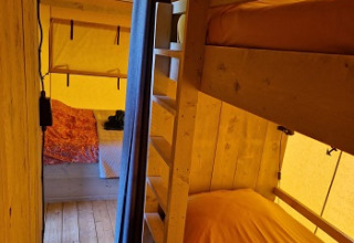 Innenaufnahme von Glamping Heemskerkerduin Safaritenten in Noord-Holland mit Etagenbett und Doppelbett.