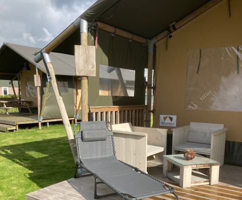 Glamping Heemskerkerduin - Safaritenten Noord-Holland met houten terras, loungeset en comfortabele ligstoel.