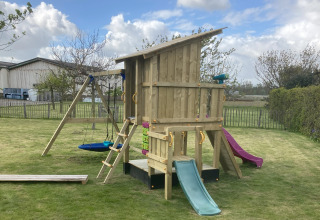 Legeplads med gyngestativ, rutsjebaner og legehus i have ved Glamping Heemskerkerduin, Safaritenten i Noord-Holland.