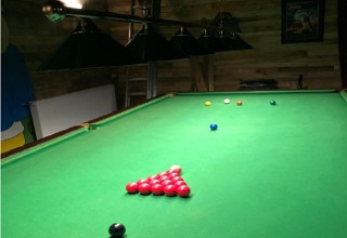 Mesa de snooker en una habitación de madera con lámparas verdes en Glamping Heemskerkerduin, Holanda Septentrional.