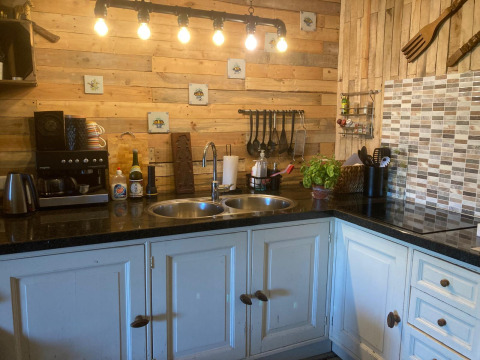 Acogedora cocina glamping en Safaritenten Noord-Holland con paredes de madera, modernos utensilios y buena luz.