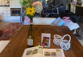 Bright kitchen with wine bottle vase, flowers, bikes, and glamping guide for Glamping Heemskerkerduin.