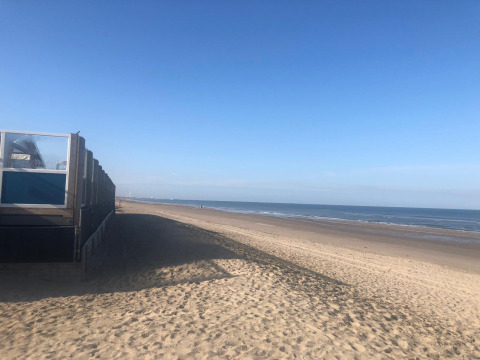 Vista de la playa en Glamping Heemskerkerduin Safaritenten Noord-Holland con cielo despejado y arena.
