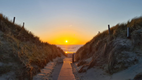 Solnedgang ved indgangen til stranden ved Heemskerkerduin, ideelt for glamping og safaritelt-camping i Holland.