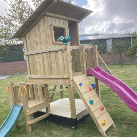 Legeplads med trætårn, klatrevæg, lilla rutsjebane og grøn rutsjebane på Glamping Heemskerkerduin.