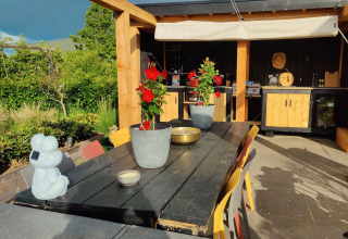 Außenbereich bei Glamping Heemskerkerduin Safarizelten Nordholland mit gedecktem Tisch und Küche.